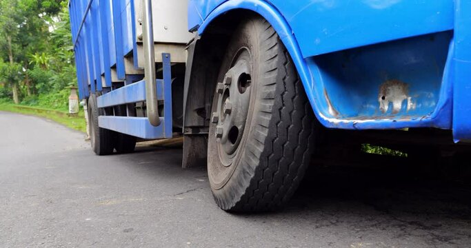 The small truck was too overloaded and its front wheel axle broke, now standing on edge of rural road. Close view of front left wheel in bent position, vehicle broke