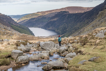 Female hiker admiring mountainous lake in Glendalough