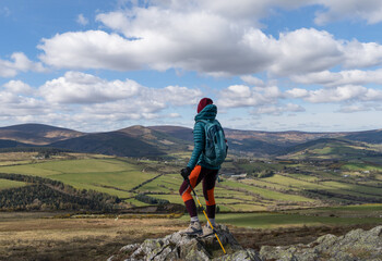 female hiker standing on top of mountain admiring landscape