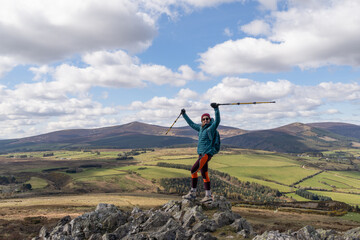 female hiker standing on top of mountain smiling triumphantly