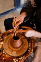 potter with a student on the potter's wheel makes dishes from clay