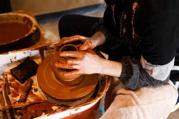 potter with a student on the potter's wheel makes dishes from clay