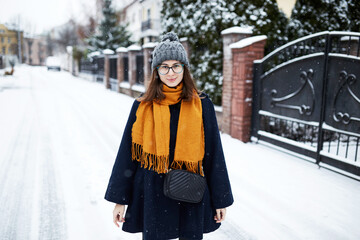 Fototapeta na wymiar woman in yellow scarf and blue coat in middle of snowy street