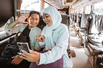 muslim couple using phone while travel by bus during eid mubarak holiday to meet family at home