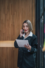 Young asian businesswoman using the tablet to analyze business data while she is standing at the office.