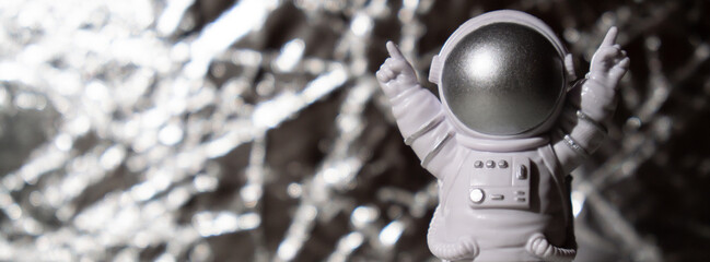 Plastic toy figure astronaut on silver background Copy space. Concept of out of earth travel,...
