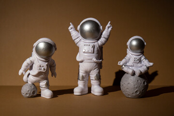 Three Plastic toys figure astronaut on beige background Copy space. Concept of out of earth travel, private spaceman commercial flights. Space missions and Sustainability