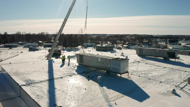 Aerial, industrial rooftop HVAC unit being installed on an office building during winter