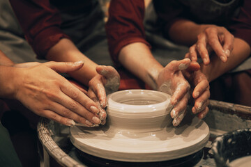 three women are working on a potter's wheel, making a vase.