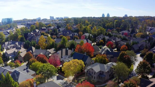 Aerial drone shot slowly rotating around a neighborhood filled with trees and Fall colors. Filmed in Sandy Springs near Atlanta, Georgia.