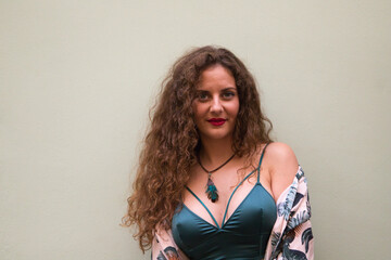 young blonde woman with curly hair and blue eyes making different gestures and expressions in front of a beige wall. Concept expressions.