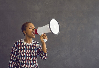 Angry mad young African American woman hold loudspeaker make announcement of deal or sale. Millennial gen z ethnic girl feel motivated get attention screen yell in speaker about good promotion. - obrazy, fototapety, plakaty