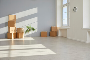 Empty room with moving cardboard boxes on floor. Boxes with belongings stacked in empty apartment against blank wall. Moving day