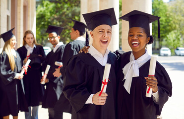 Happy smiling caucasian man afroamerican woman in graduation gown and cap graduate universuty with...