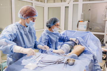 Surgeons operate on the legs of an elderly woman with varicose veins.