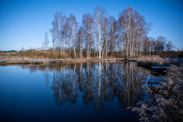 spring landscape with a lake and reflection of trees in the water on a sunny day