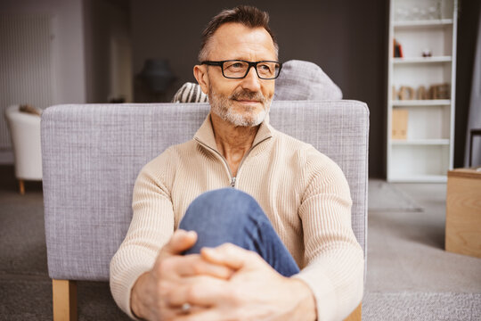 Middle-aged man sitting on living room floor and looking to the side