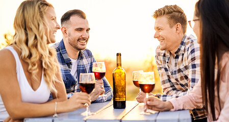 Young friends having fun outdoors - Happy people enjoying harvest time together at farmhouse winery countryside - Youth and friendship concept - Tasting red wine at vineyard before sunset