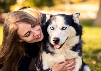 Siberian husky playing in grass outdoors with the owner girl together - Human and dog friendship and loyalty concept outside on a countryside field