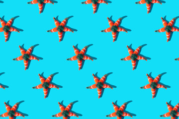Seamless pattern of starfish with sunlight shadow on bright blue background.