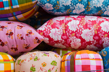 Colorful designed pillows are kept together in a store