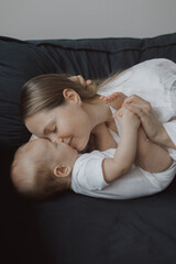 Side view of a young woman playing with her little baby in bed