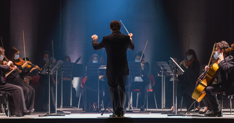Cinematic Shot of an Orchestra on a Classic Theatre Stage:  Professional Conductor Directing...