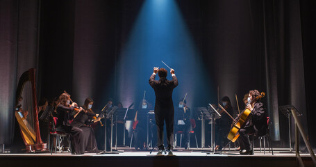 Cinematic Shot of an Orchestra on a Classic Theatre Stage:  Professional Conductor Directing...
