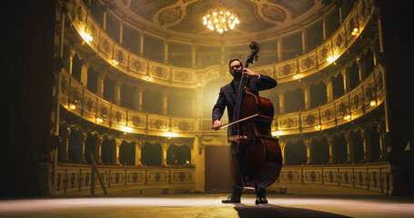 Cinematic shot of Male Cellist Playing Cello Solo on an Empty Classic Theatre Stage with Dramatic Lighting. Professional Musician Rehearsing Before the Start of a Big Show with Orchestra © Kitreel