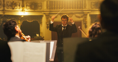 Cinematic Close Up of Conductor Directing Symphony Orchestra with Performers Playing on Stage...