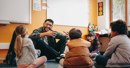Fototapeta Male educator talking to his students in a classroom. Man teaching elementary school children obraz