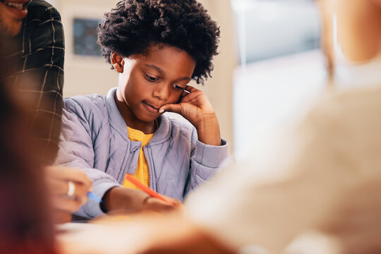 Black Kid Writing His Work In A Primary School Class