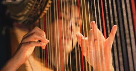 Cinematic Closeup of the Hands of a Female Harpist Playing Harp Solo Gracefully in a Dark Stage....