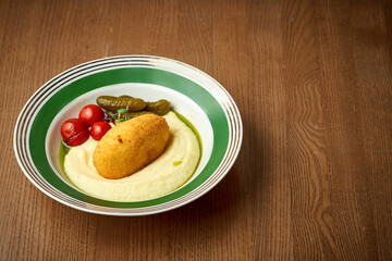 Chicken Kyiv with mashed potatoes in a plate on a wooden background