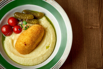 Chicken Kyiv with mashed potatoes in a plate on a wooden background