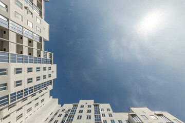 view up from ground to blue sky among skyscrapers, look at house from bottom up - obrazy, fototapety, plakaty