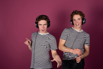 Two young attractive guys listen to music on headphones.	