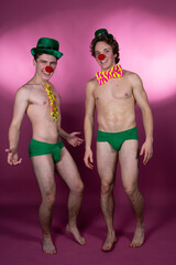 Two young attractive guys in clown costumes.	