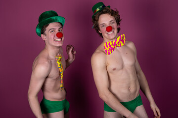 Two young attractive guys in clown costumes.	