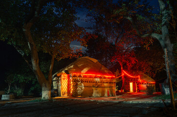 Night photo of illuminated yurts in an apricot orchard at a campsite in the Kyrgyz village of Ozgrush.