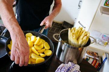 old man cooking asparagus in the kitchen