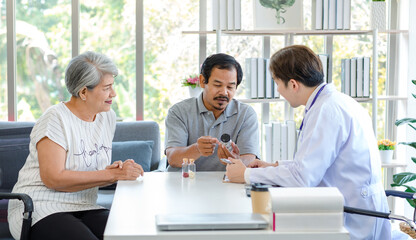 Asian professional successful male doctor in white lab coat with stethoscope hold medicine pill bottle showing explaining dosage and usage to elderly old senior patient and cousin in hospital office