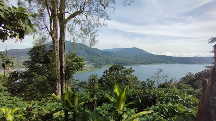 Fototapeta na wymiar Bali Island, Indonesia 09 April 2023 - beautiful lake between green hills and natural forest.