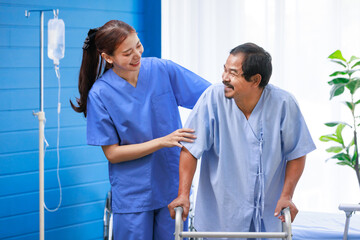 Asian professional successful female internship nurse in blue uniform smiling visiting helping supporting old senior elderly pensioner male patient physical therapy walking with four legged walker