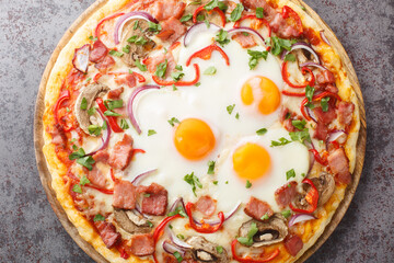 Hot pizza with bacon, eggs, peppers, mushrooms, mozzarella and red onions close-up on a wooden board on the table. Horizontal top view from above