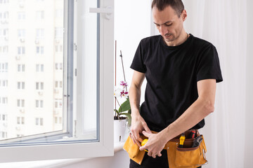Young repairman fixing window frame in room at daytime