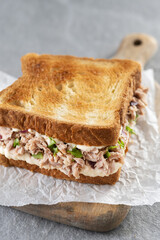 Tuna sandwich with mayo and vegetables on gray stone background.