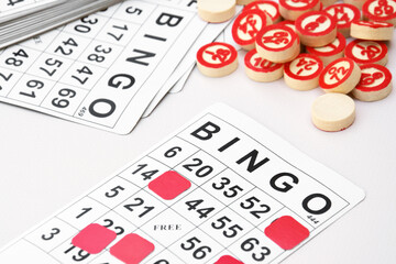 Many wooden chips with numbers and cards for a board game of bingo or lotto on a light background.