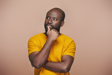 Portrait of African American man contemplating about something standing against brown background