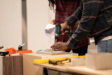 Crop man hand using drill with peace of wood professionally in factory, employee do their work at work place, labor do hard work.